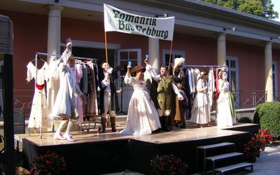 Oper in der Romantik Bad Rehburg Die Oper in der Romantik Bad Rehburg. Vor der Kuranlage stehen Menschen in historischer Tracht.