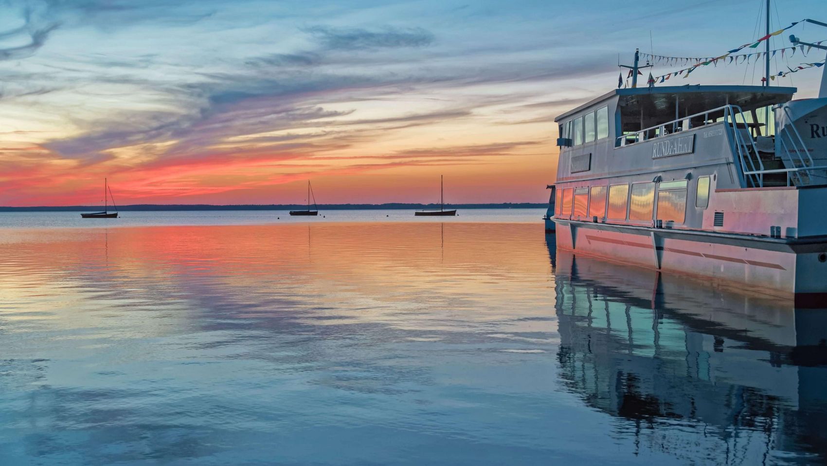 Abendstimmung Fahrgastschiff Auswanderer Das Fahrgastschiff liegt am Steg, im Hintergrund ankern Auswanderer im Sonnenuntergang.