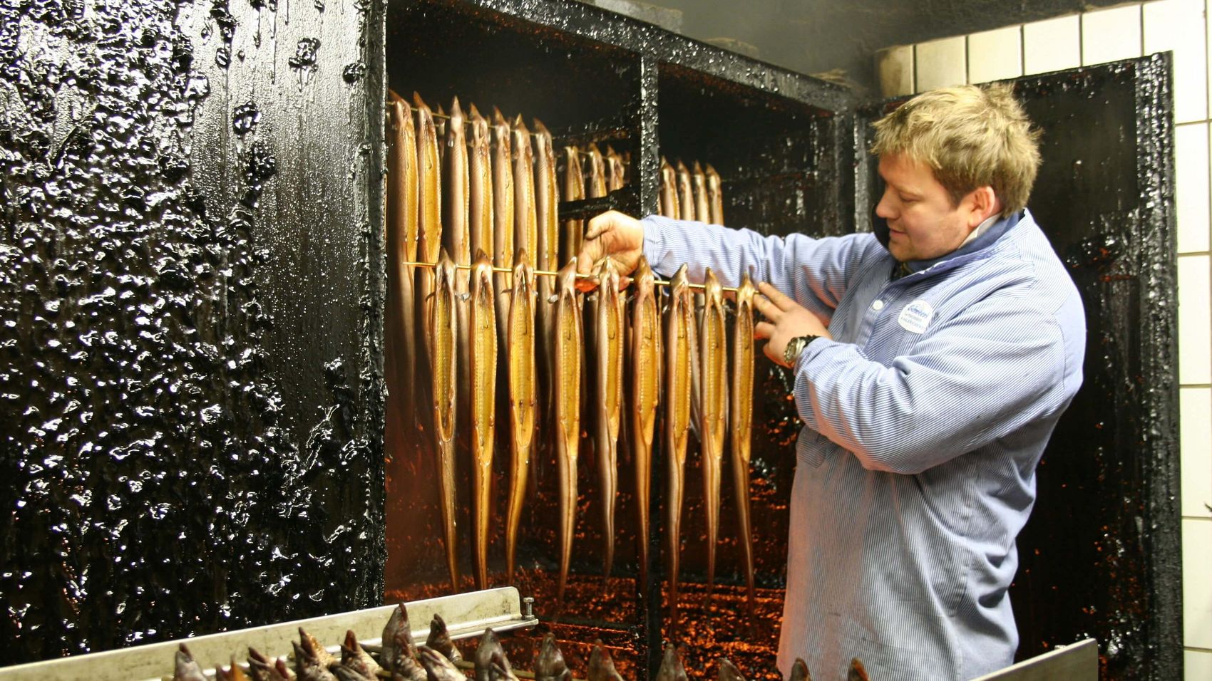 Aalräucherei Ein Fischer hält frische Räucheraale vor einem Altonaer Räucherofen in der Hand