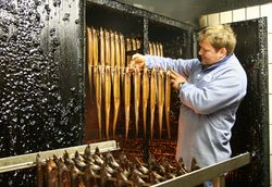 Ein Fischer hält frische Räucheraale vor einem Altonaer Räucherofen in der Hand
