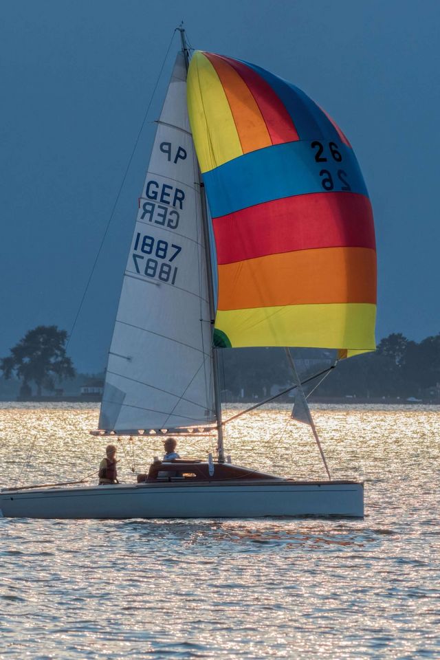 Ein Boot segelt vor dem Wilhelmstein entlang. Ein Boot mit einem Ballonsegel segelt am späten Nachmittag vor dem Wilhelmstein entlang.