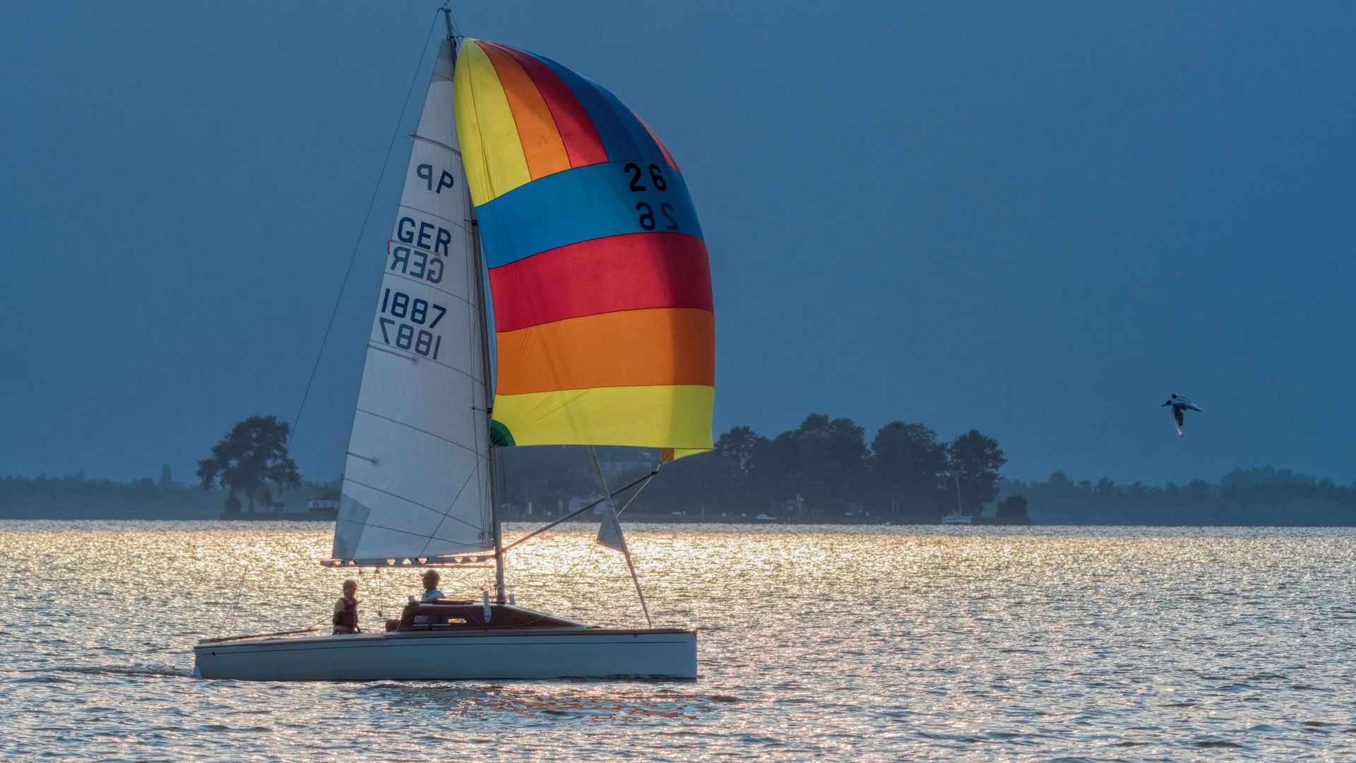 Ein Boot mit einem Ballonsegel segelt am späten Nachmittag vor dem Wilhelmstein entlang.