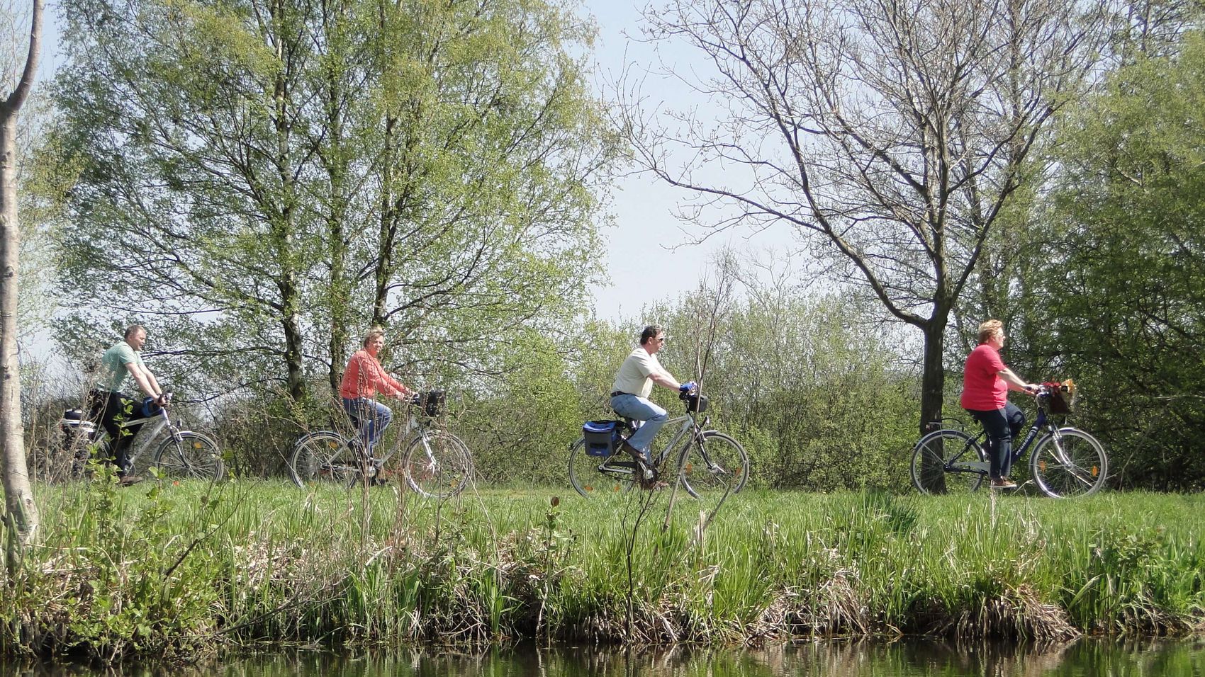 Fahrradfahrer am Hagenburger Kanal Fahrradfahrer radeln an einem schönen Frühlingstag am Hagenburger Kanal entlang und spiegeln sich in der Wasseroberfläche