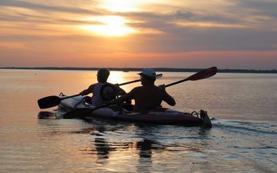 Kanufahrer im Sonnenuntergang Ein Pärchen fährt im Zweierkanu dem Sonnenuntergang entgegen