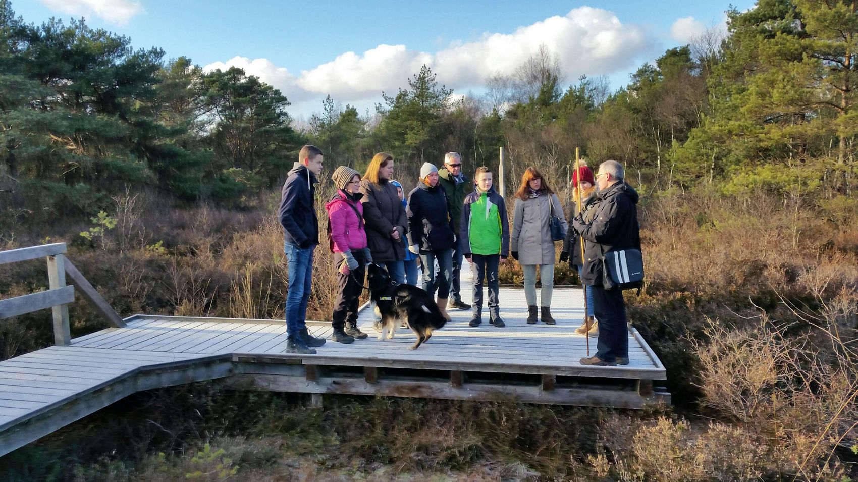 I want Moor Eine Gruppe mit einem Hund hört wissbegierig auf der Moorwanderung über den Moorerlebnispfad zu