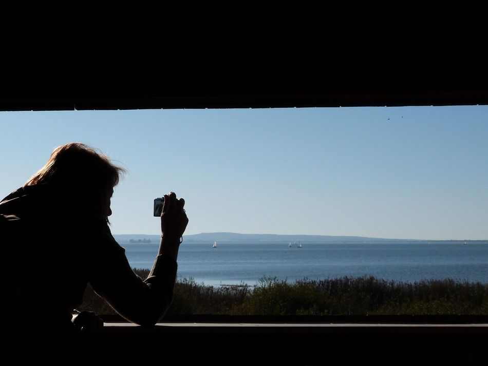 Aussichtsturm Ostenmeer Eine Frau fotografiert aus dem Aussichtsturm im Ostenmeer die Landschaft, mit weitem Blick über das Steinhuder Meer bei strahlendem Sonnenschein
