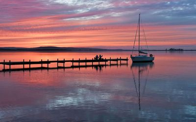 Abendrot auf dem Steg Ein Paar sitzt im Abendrot auf einem Steg an dem ein Segelboot festgemacht hat