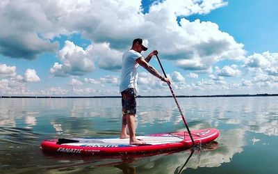 Stand Up Paddling Ein Mann macht Stand Up Paddling auf dem Steinhuder Meer, im Hintergrund blauer Himmel mit vielen Wolken