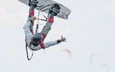 Kitesurfer im Sprung Ein Kitesurfer ist Sprung über der Wasseroberfläche und streckt einen Arm von sich.