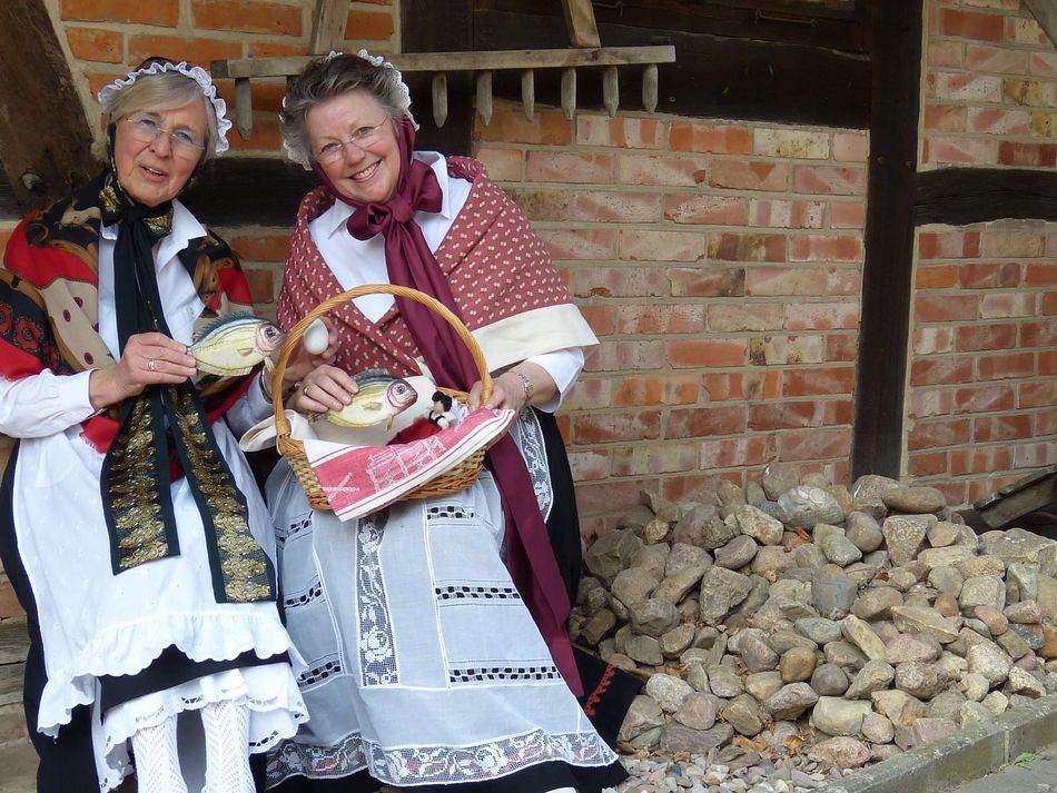 Steinhuder Gästeführerinnen in Tracht Zwei Seinhuder G ästeführerinnen sitzen zusammen in Tracht vor dem Museum der Steinhuder Kastenmangel im Sonnenlicht