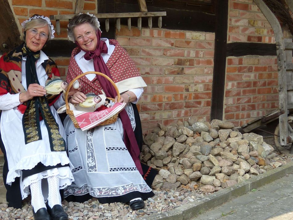 Steinhuder Gästeführerinnen in Tracht Zwei Seinhuder G ästeführerinnen sitzen zusammen in Tracht vor dem Museum der Steinhuder Kastenmangel im Sonnenlicht
