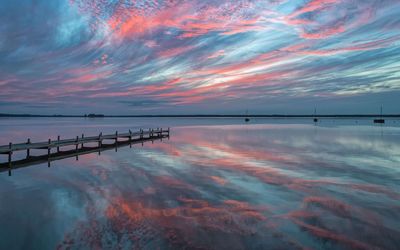 Abendstimmung Wolkenhimmel Steg Der abendliche Wolkenhimmel mit Sonnenuntergang spiegelt sich auf der Wasserfläche, Im Hintergrund ist ein Steg.