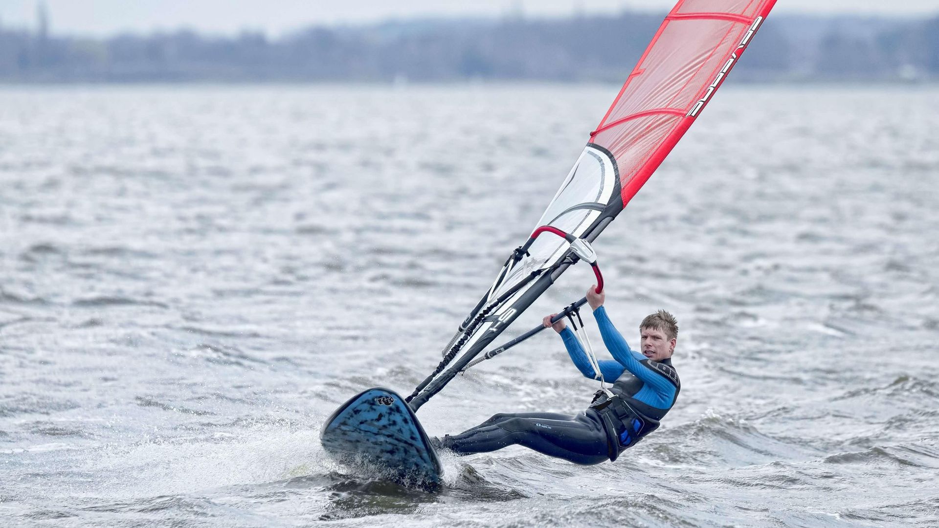 Ein Windsurfer ist auf dem Meer unterwegs.