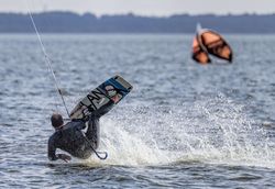 Ein Kitesurfer gleitet über die Wasseroberfläche.