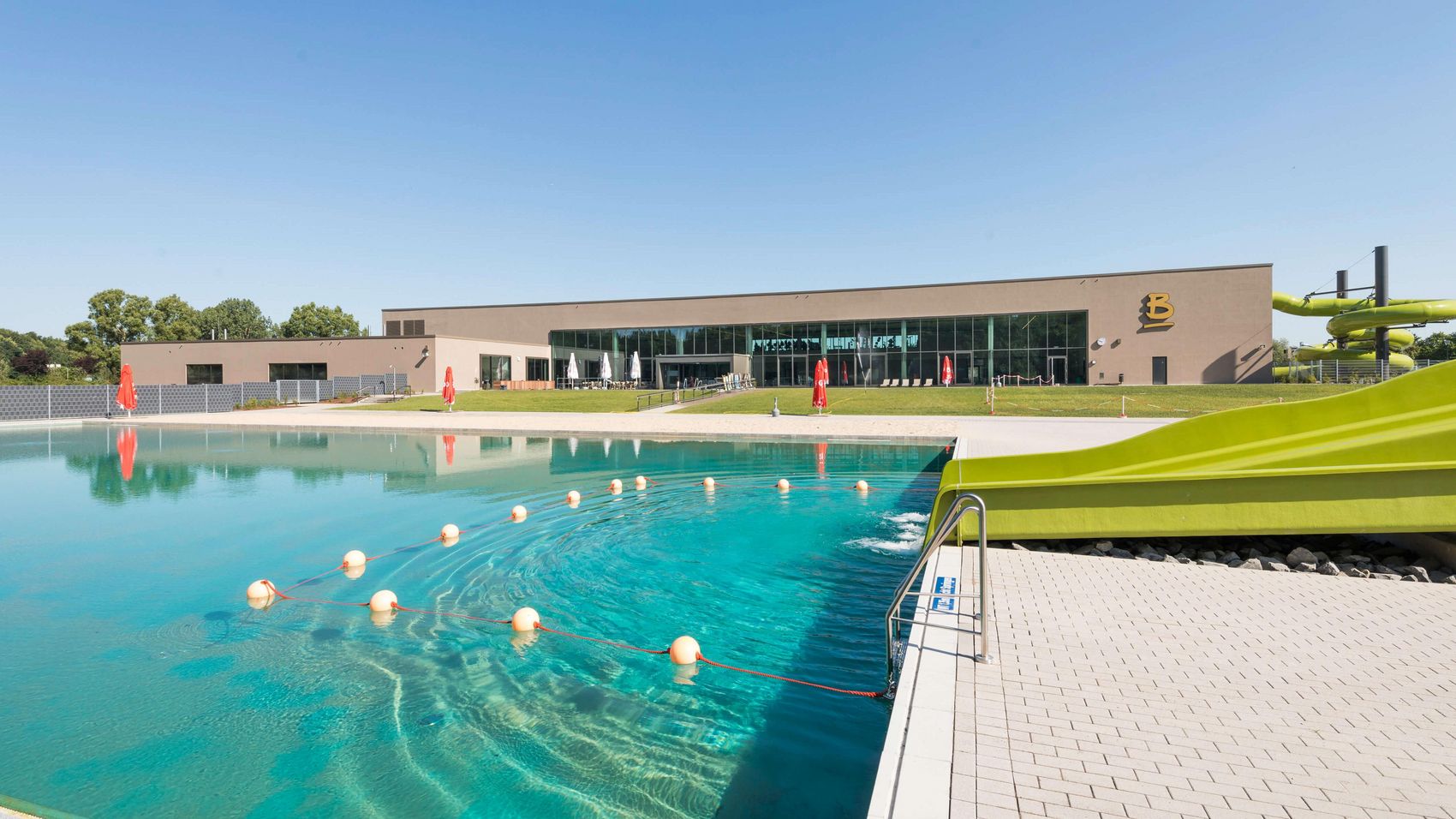 Balneon Neustadt Hallen- und Freibad Blaues Wasser im Freibad Balneon in Neustadt mit grüner Wasserrutsche im Vordergrund