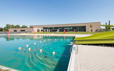 Balneon Neustadt Hallen- und Freibad Blaues Wasser im Freibad Balneon in Neustadt mit grüner Wasserrutsche im Vordergrund