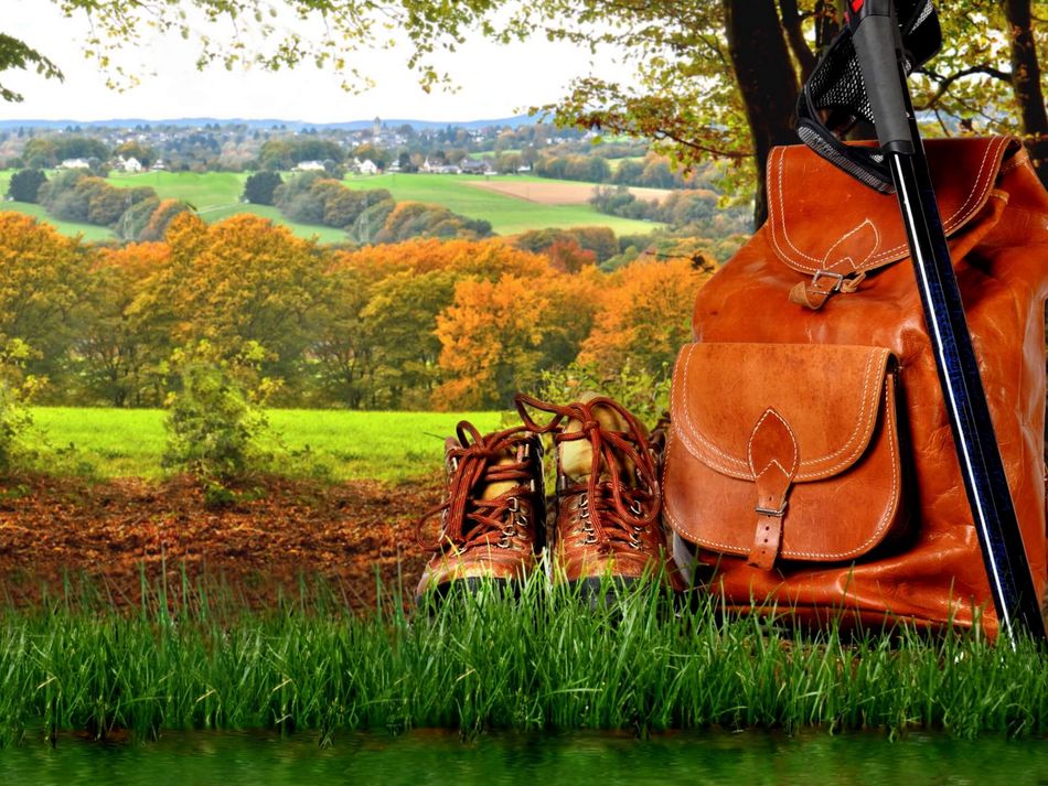 Wandern Wanderschuhe, Wanderrucksack und Wanderstock vor herbstlicher Kulisse