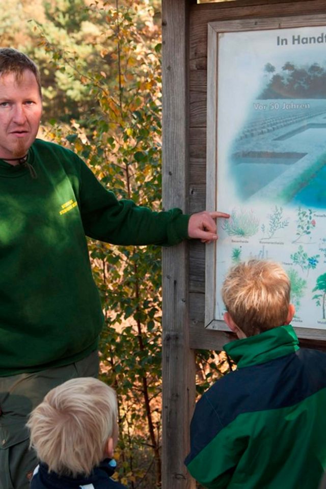 Gruppenführung mit Ranger Der Naturparkranger zeigt einer Gruppe an einer Schautafel den Aufbau des Moores