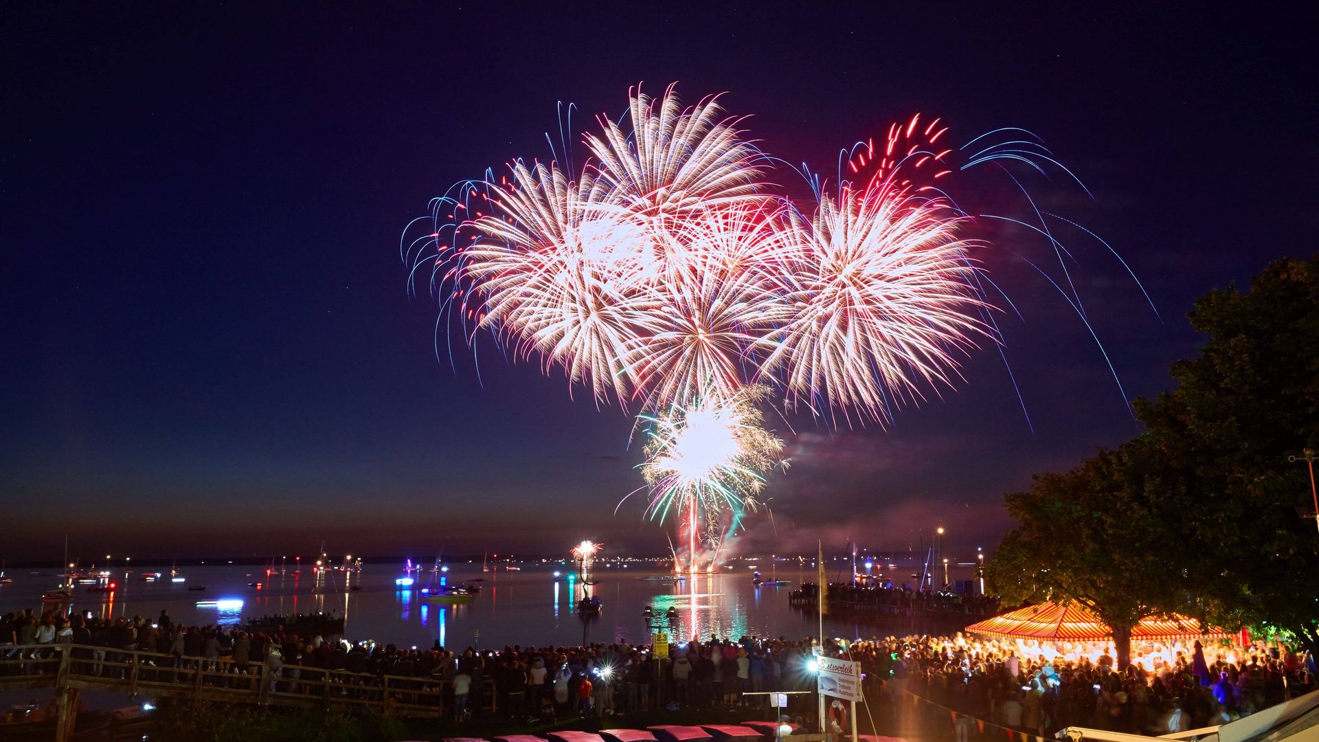 Rote und rosa Feuerwerksfontainen begeistern die Zuschauer des Feuerwerks vor der Promenade in Steinhude